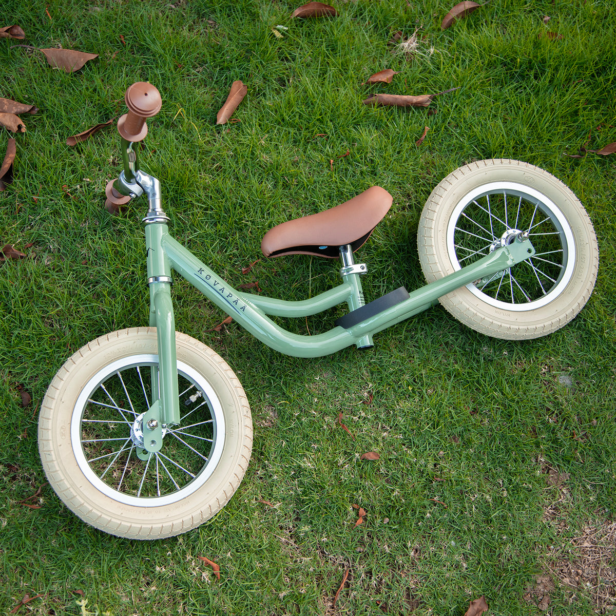 Køvapää groene 2-in-1 loopfiets buiten in het gras gefotografeerd (andere hoek)