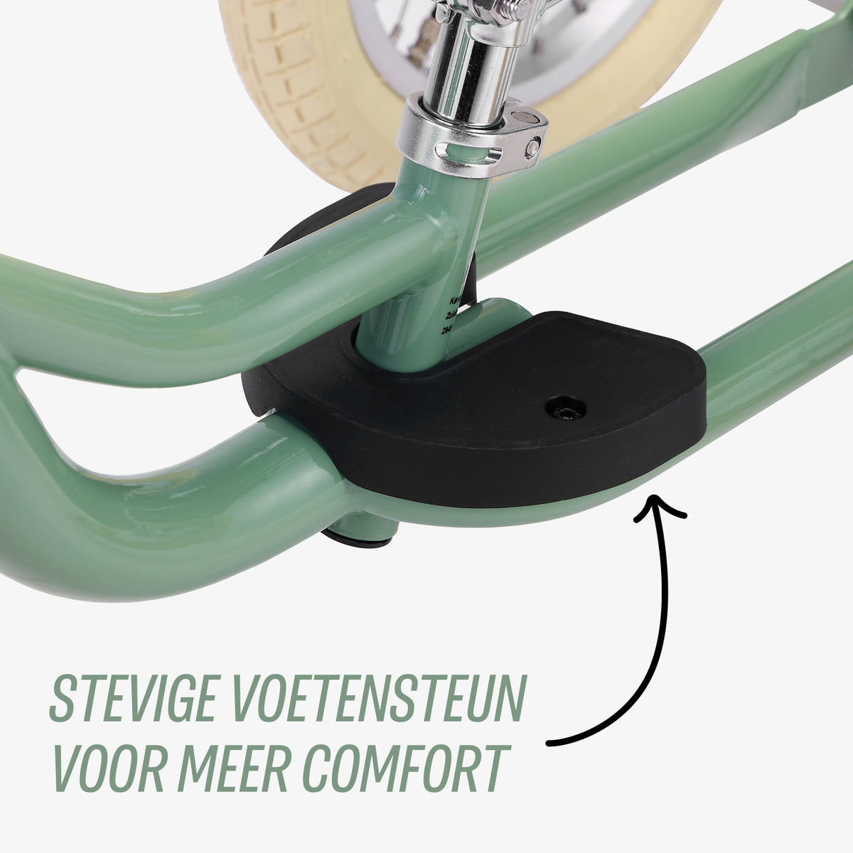 close-up van voetensteunen op groene Køvapää 2-in-1 loopfiets