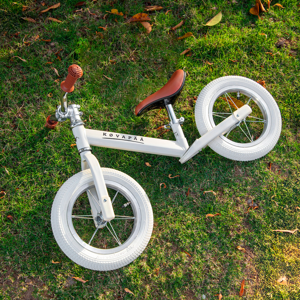 beige Køvapää loopfiets buiten in het gras gefotografeerd